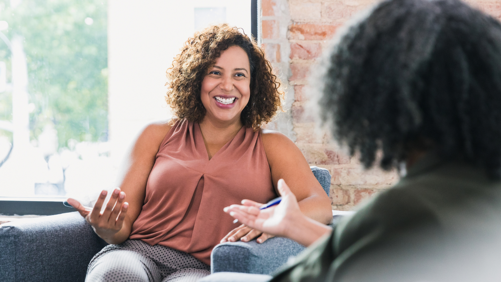 A woman sat next to a woman, smiling and talking