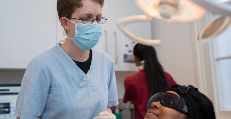 Dentist wearing a face mask, with a patient