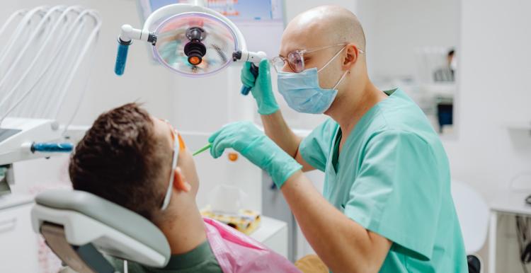 Dentist wearing a face mask looking at patients mouth