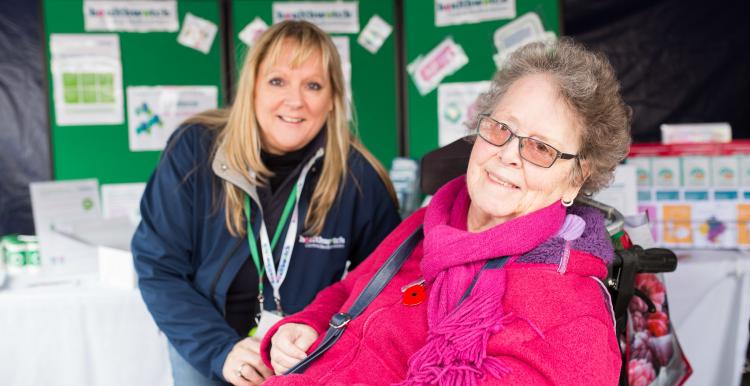 Healthwatch staff member at event talking to someone in a wheelchair