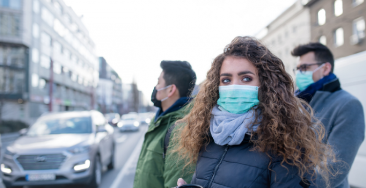 A group of young adults wearing face masks whilst stood outside