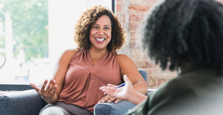 A woman sat next to a woman, smiling and talking