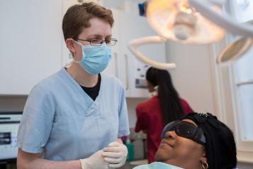 Dentist wearing a face mask, with a patient