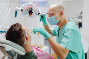 Dentist wearing a face mask looking at patients mouth