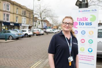 Volunteer standing in front of a pop up banner