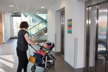 Woman pushing a push chair and waiting for a lift in a hospital 