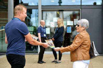 A member of the public being handed a leaflet outside of the Eccles Library