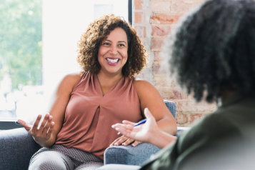 A woman sat next to a woman, smiling and talking