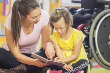 A woman reading a book to a young girl