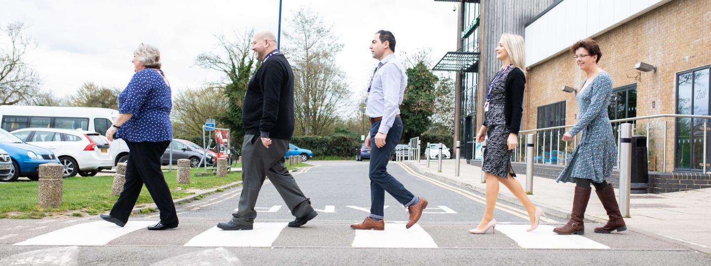 Staff members walking across a zebra crossing 